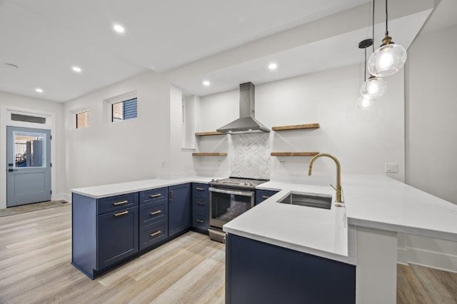 kitchen featuring wall chimney range hood, pendant lighting, stainless steel electric range, kitchen peninsula, and sink