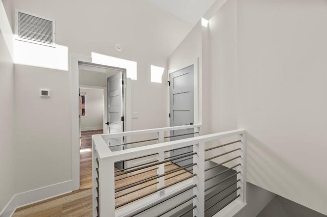 hallway with lofted ceiling and hardwood / wood-style flooring