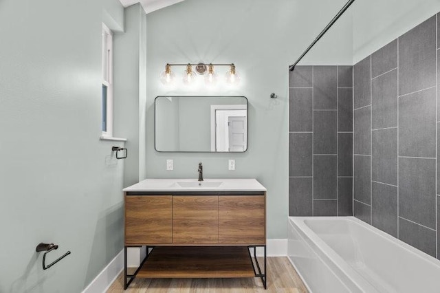 bathroom with hardwood / wood-style floors, tiled shower / bath combo, and vanity