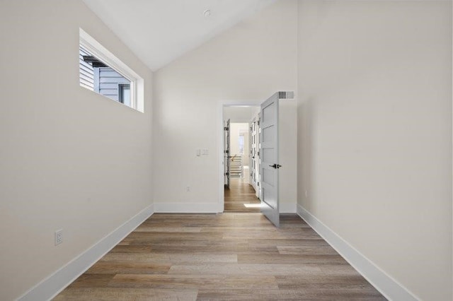 empty room with vaulted ceiling and light hardwood / wood-style flooring