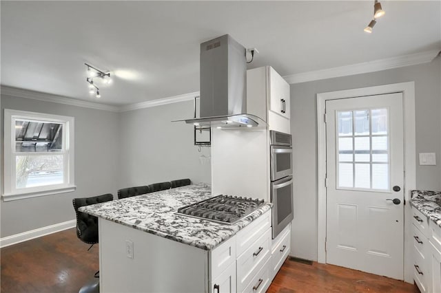 kitchen with appliances with stainless steel finishes, island range hood, white cabinets, and light stone countertops