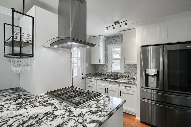 kitchen with light stone countertops, white cabinets, appliances with stainless steel finishes, island exhaust hood, and sink