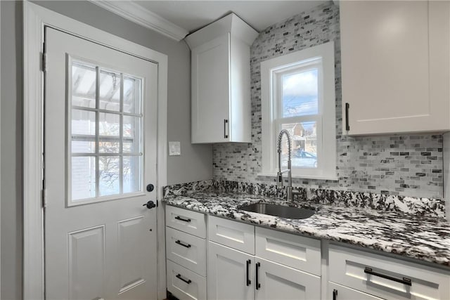 kitchen with white cabinetry, crown molding, stone countertops, and sink