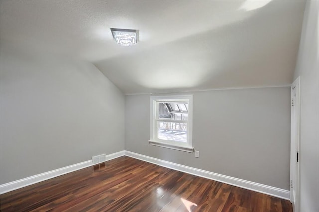 additional living space featuring dark hardwood / wood-style flooring and vaulted ceiling