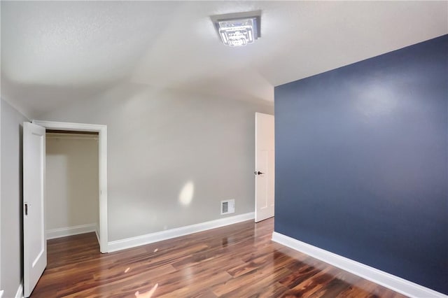 spare room featuring lofted ceiling and dark wood-type flooring