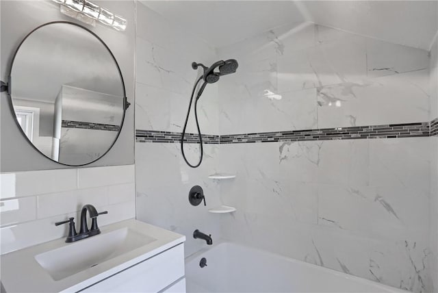 bathroom featuring decorative backsplash, tiled shower / bath, and vanity