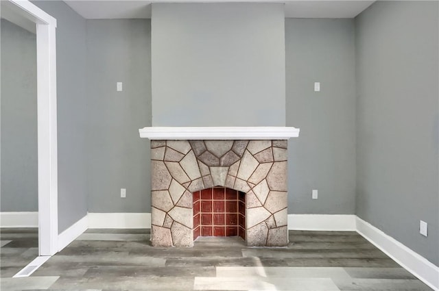 room details with hardwood / wood-style floors and a stone fireplace