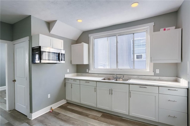 kitchen with sink, white cabinets, and light wood-type flooring