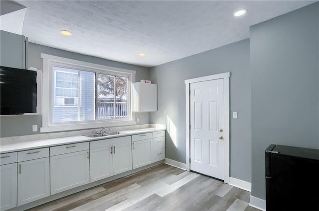 kitchen with sink, white cabinetry, and light hardwood / wood-style flooring