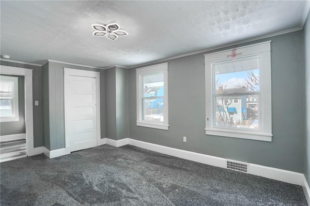 unfurnished bedroom with a textured ceiling, crown molding, dark carpet, and multiple windows