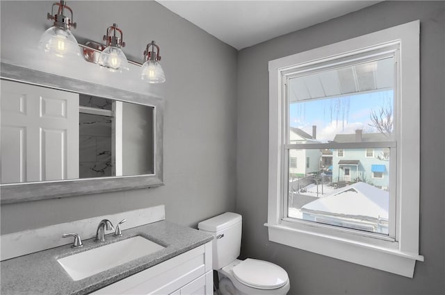 bathroom with toilet, plenty of natural light, and vanity