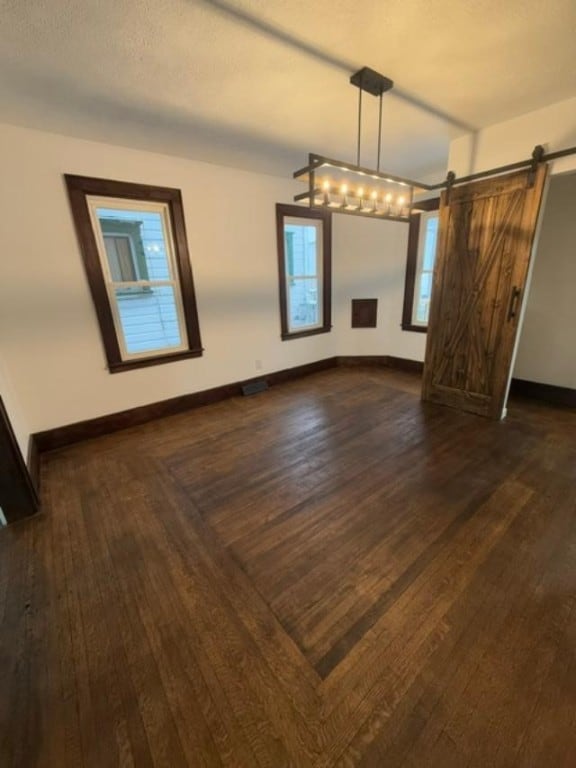 unfurnished dining area featuring dark wood-type flooring and a barn door