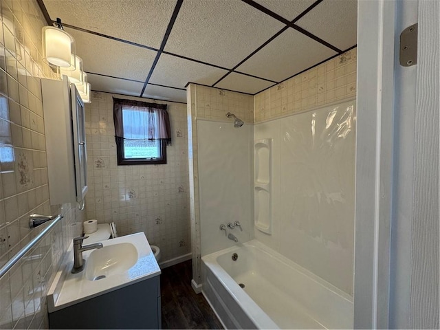 full bathroom with shower / bathing tub combination, a paneled ceiling, wood-type flooring, vanity, and toilet