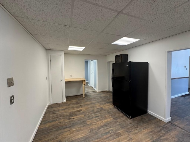 kitchen with black refrigerator, a drop ceiling, and dark hardwood / wood-style flooring