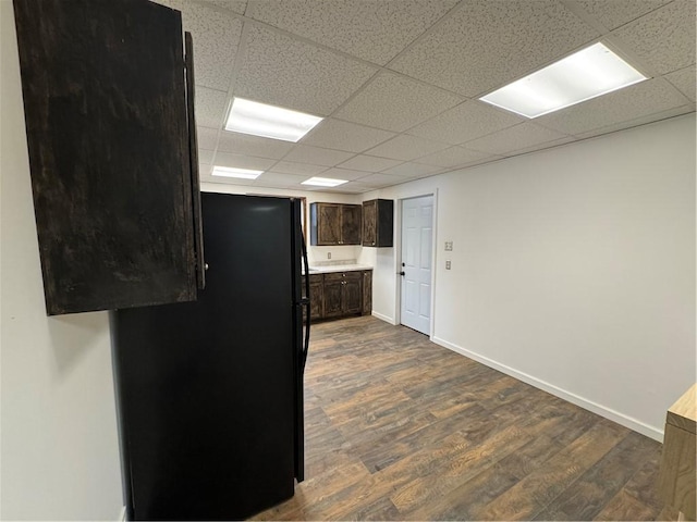 kitchen featuring dark hardwood / wood-style flooring, dark brown cabinets, a drop ceiling, and black refrigerator