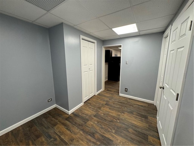 interior space with a drop ceiling and dark hardwood / wood-style floors