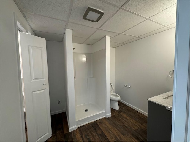 bathroom featuring a paneled ceiling, vanity, toilet, walk in shower, and hardwood / wood-style flooring