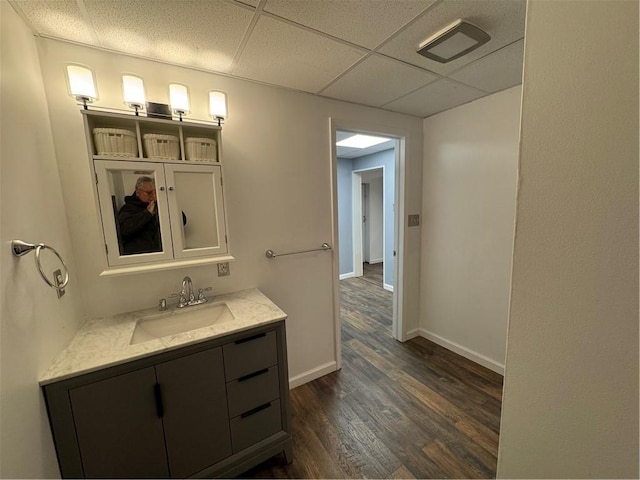 bathroom featuring a paneled ceiling, wood-type flooring, and vanity