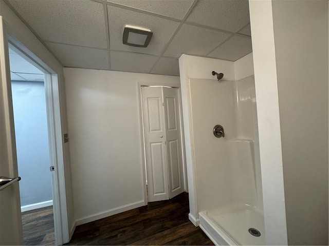 bathroom with hardwood / wood-style flooring, a drop ceiling, and walk in shower