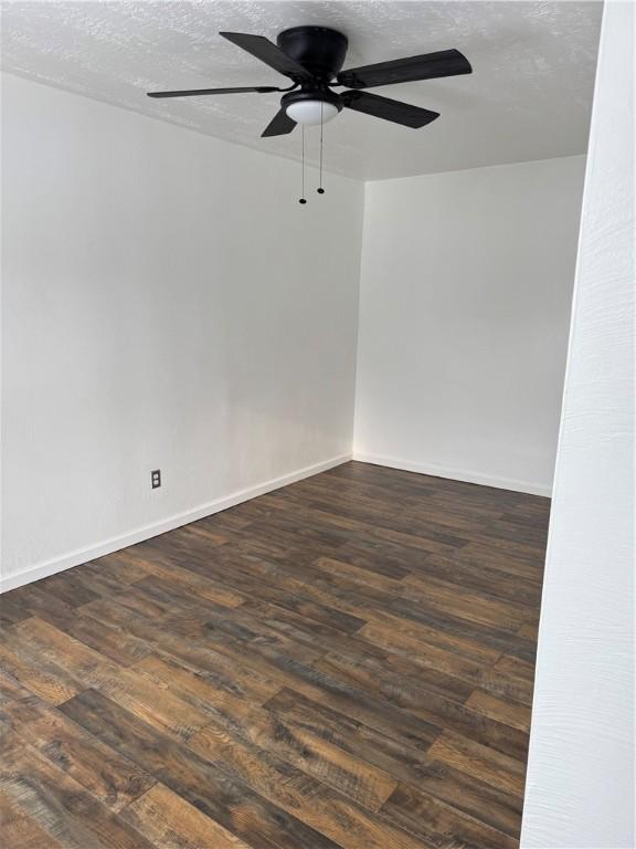 unfurnished room with a textured ceiling, dark wood-type flooring, and ceiling fan