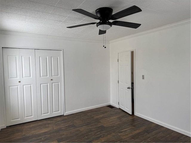 unfurnished bedroom with ceiling fan, ornamental molding, a closet, and dark hardwood / wood-style floors