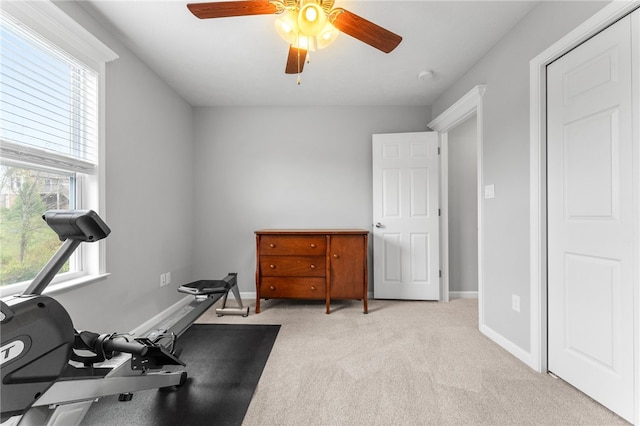 exercise room with ceiling fan and light colored carpet