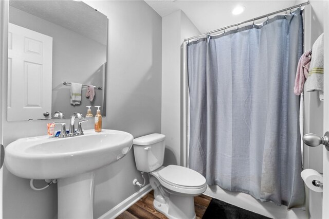 bathroom featuring toilet, shower / bath combination with curtain, and hardwood / wood-style floors