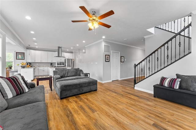 living room with ceiling fan, crown molding, and light hardwood / wood-style floors