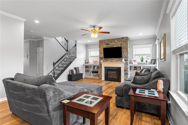 living room featuring ceiling fan, ornamental molding, a fireplace, and wood-type flooring