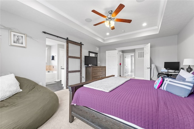 carpeted bedroom with ensuite bathroom, a barn door, ceiling fan, a tray ceiling, and ornamental molding