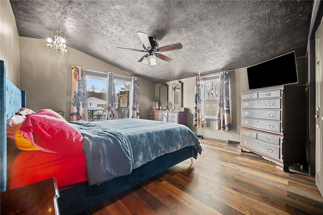 bedroom featuring vaulted ceiling, ceiling fan with notable chandelier, a textured ceiling, and hardwood / wood-style flooring