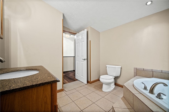 bathroom with tiled bath, vanity, tile patterned flooring, toilet, and a textured ceiling