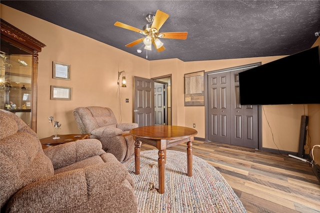 living room featuring ceiling fan, vaulted ceiling, and light hardwood / wood-style floors