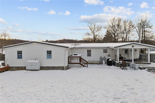 snow covered back of property with a wooden deck