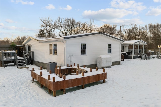 snow covered property with central air condition unit and a deck