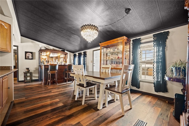 dining room with lofted ceiling, dark hardwood / wood-style flooring, bar, and a notable chandelier