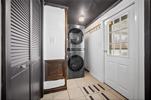 washroom with stacked washer and dryer and light tile patterned floors