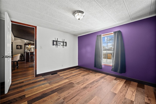 empty room featuring dark hardwood / wood-style flooring and a textured ceiling