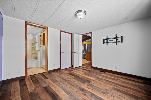 unfurnished bedroom featuring hardwood / wood-style floors, ensuite bathroom, and a textured ceiling