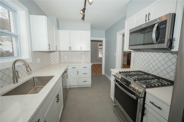 kitchen with decorative backsplash, sink, light stone countertops, appliances with stainless steel finishes, and white cabinets