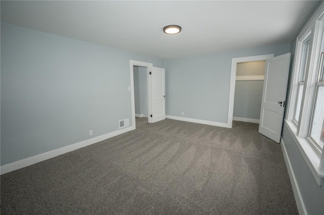 unfurnished bedroom featuring a closet and dark carpet