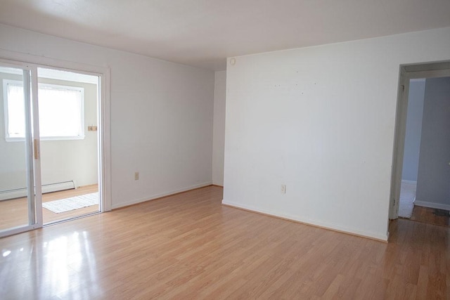 empty room featuring a baseboard heating unit and light hardwood / wood-style floors