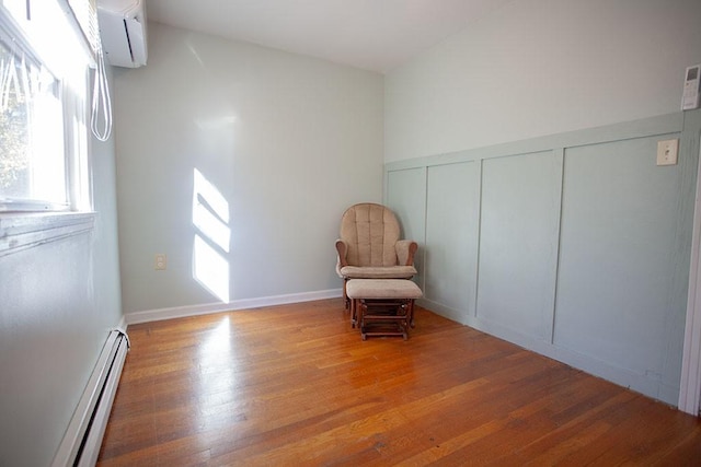 unfurnished room with baseboard heating, a wall mounted air conditioner, and wood-type flooring