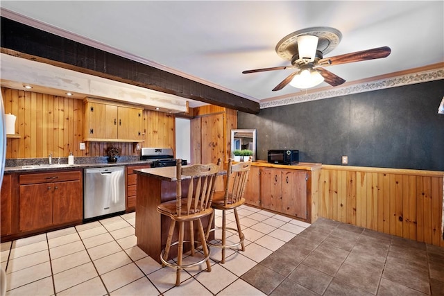 kitchen with stainless steel appliances, wooden walls, sink, ornamental molding, and a breakfast bar area