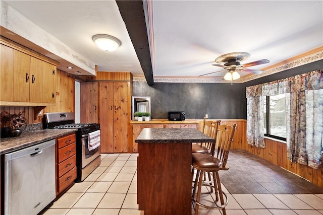 kitchen featuring ceiling fan, light tile patterned floors, appliances with stainless steel finishes, and a breakfast bar area