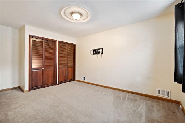 unfurnished bedroom with light colored carpet, visible vents, and baseboards