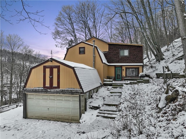 colonial inspired home with a barn, a shingled roof, a detached garage, and a gambrel roof