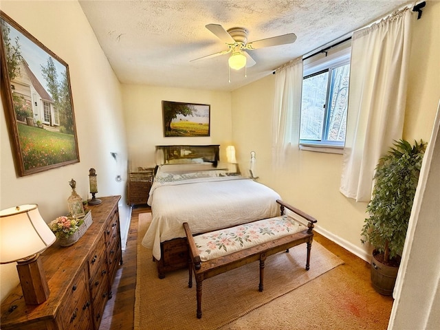 bedroom with a textured ceiling, wood finished floors, a ceiling fan, and baseboards