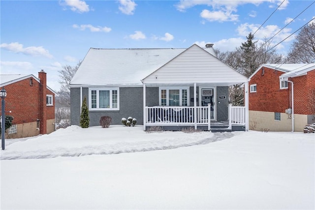 snow covered back of property featuring covered porch