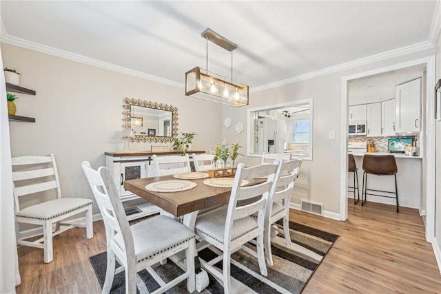 dining area featuring crown molding and light hardwood / wood-style flooring